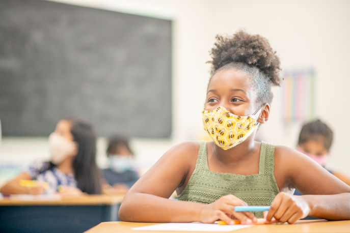 Young student in a classroom wearing a mask