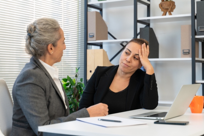 Unhappy businesswoman seated with manager having a discussion.