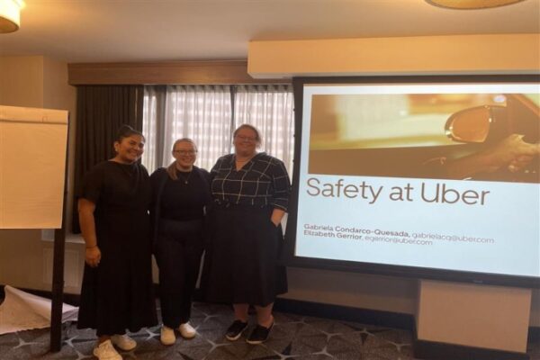 RALIANCE team member with Uber representatives posed in front of their Powerpoint presentation.